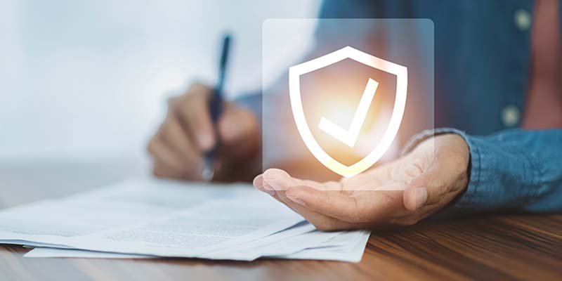person holding a shield with a checkmark while signing paperwork